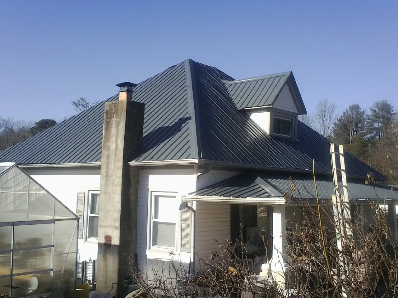 Dark blue standing seam metal roof on a white farmhouse with dormer — Slate & Tile Roof Repair by Roofing Brothers in Homerville