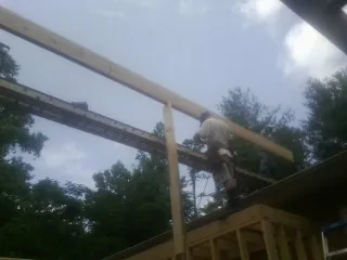 Carpenter setting a ridge beam over a new addition frame — Ice Dam Removal by Roofing Brothers in Homerville