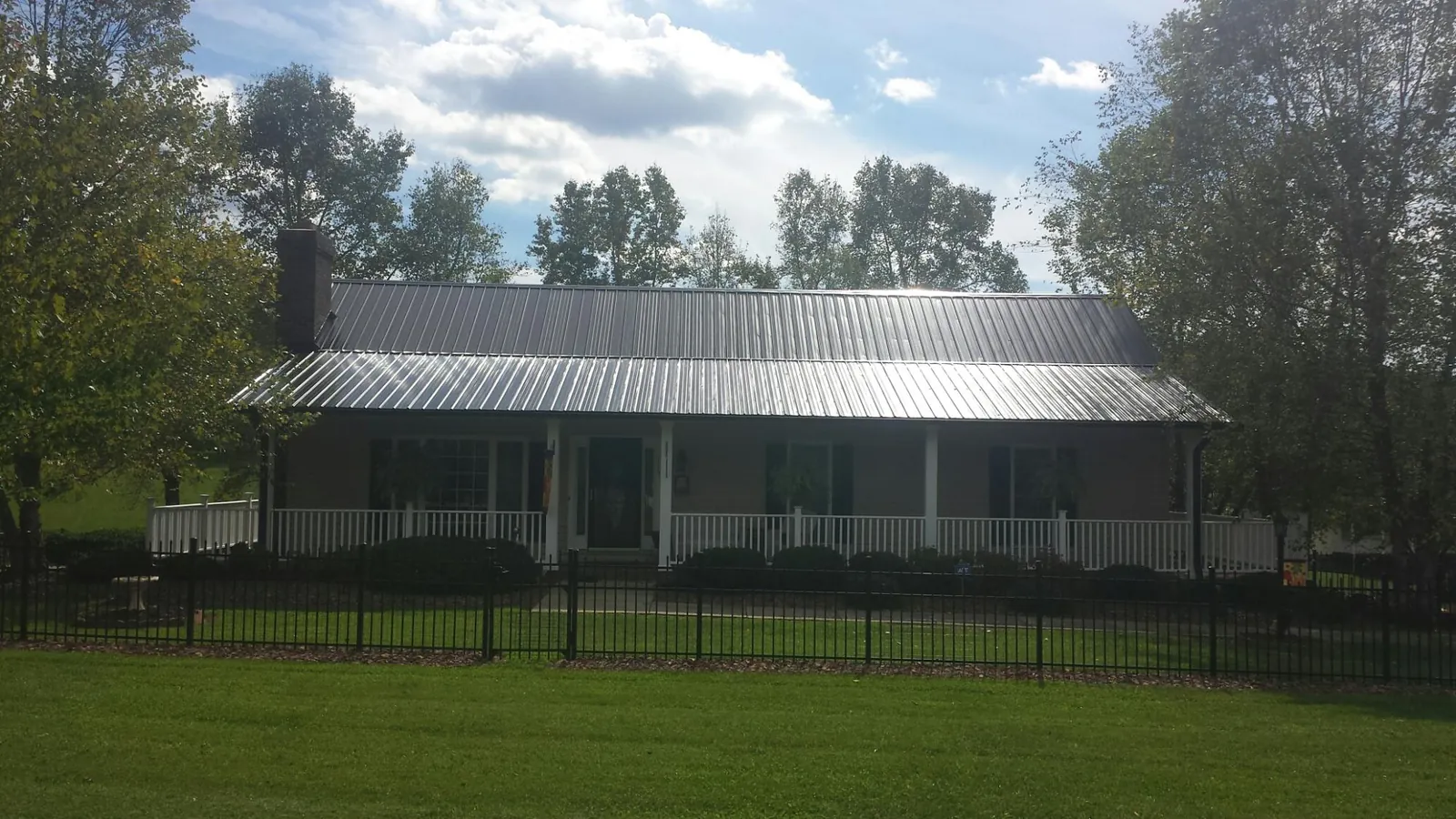 Gray metal roof on a brick ranch with a full width front porch — Gutter Guard Installation work by our crew in Homerville